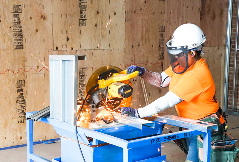 Construction working using saw to cut metal
